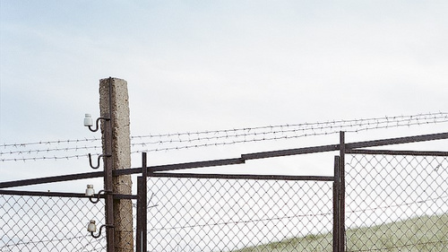 Das Bild zeigt einen Grenzzaun auf einem H&uuml;gel